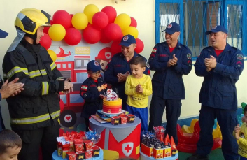 Notícia - Em Criciúma, criança de quatro anos recebe visita surpresa durante festa com o tema de Bombeiro Militar